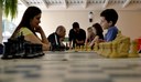 Pais e alunos se encontram para jogar xadrez em oficina